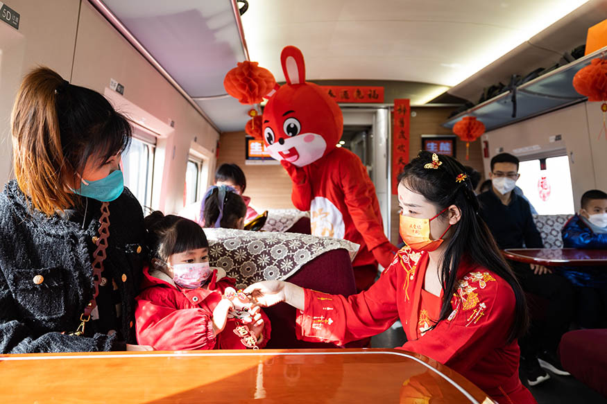 西安北至深圳北G824次列車,高鐵乘務(wù)員裝扮成“嫦娥”為小旅客贈送兔年主題掛飾。劉翔 攝