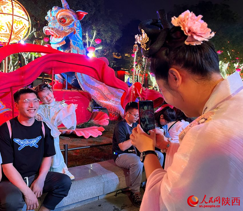 游客在大唐不夜城景區(qū)內(nèi)拍照留念。人民網(wǎng)魏鑫 攝