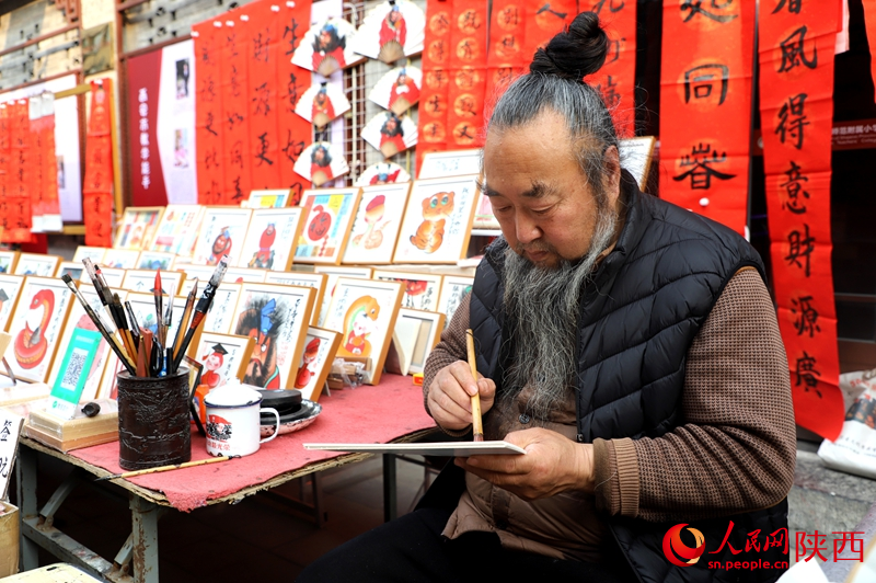 書院門步行街?jǐn)傊髡诶L制蛇年畫作。人民網(wǎng)記者 孫挺攝