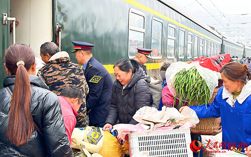 列車長(zhǎng)幫助村民把背簍抬上車。人民網(wǎng)記者 白鴿攝