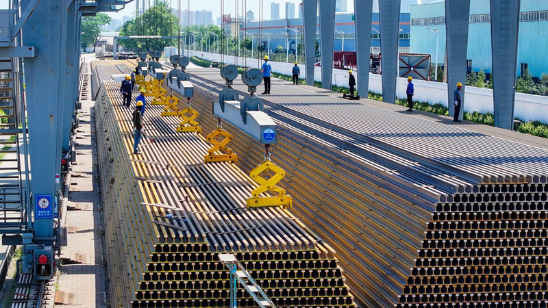 基地工人正在對(duì)100米鋼軌母材進(jìn)行卸車(chē)作業(yè)。劉剛攝