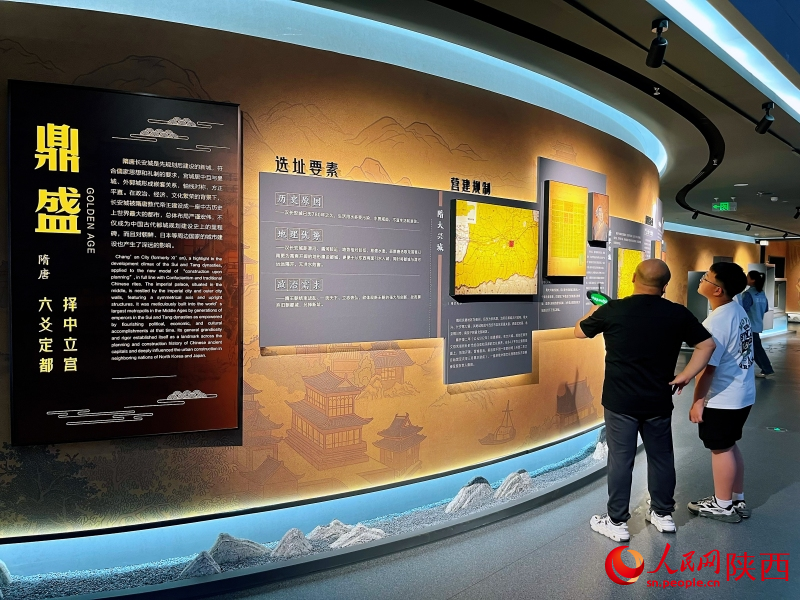 在西安城市規(guī)劃展覽館，市民給孩子講解唐長(zhǎng)安城的營(yíng)建規(guī)制。 人民網(wǎng)記者 魏鑫攝