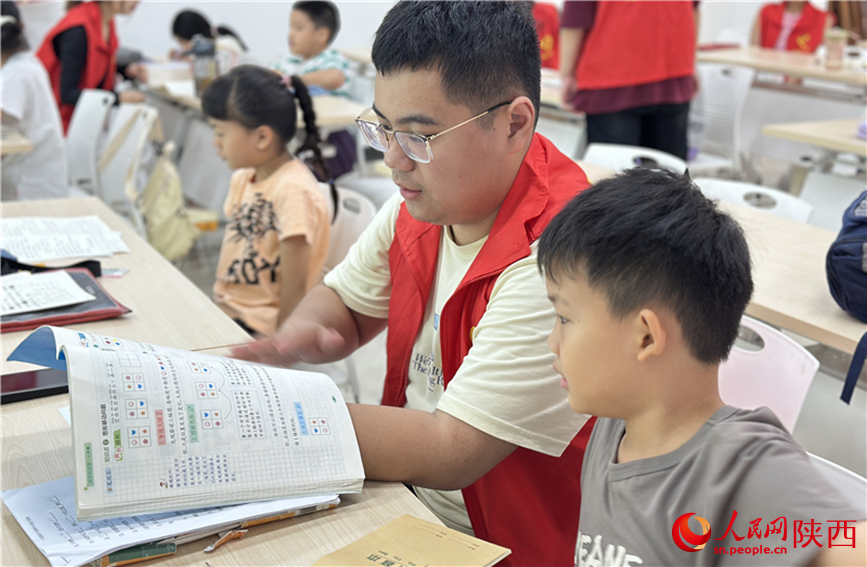 7月16日，西安市新城區(qū)明宮社區(qū)的志愿者在給孩子輔導(dǎo)作業(yè)。人民網(wǎng)記者 李志強(qiáng)攝