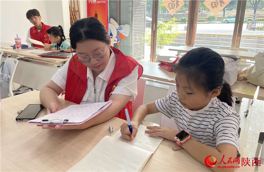 7月16日，西安市新城區(qū)明宮社區(qū)的志愿者在給孩子輔導(dǎo)作業(yè)。人民網(wǎng)記者 李志強(qiáng)攝