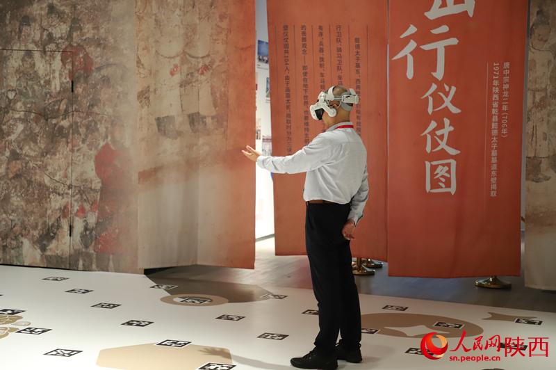 一名《壁畫那邊是唐朝》項(xiàng)目的體驗(yàn)者正在和劇情互動。人民網(wǎng)記者 李志強(qiáng)攝